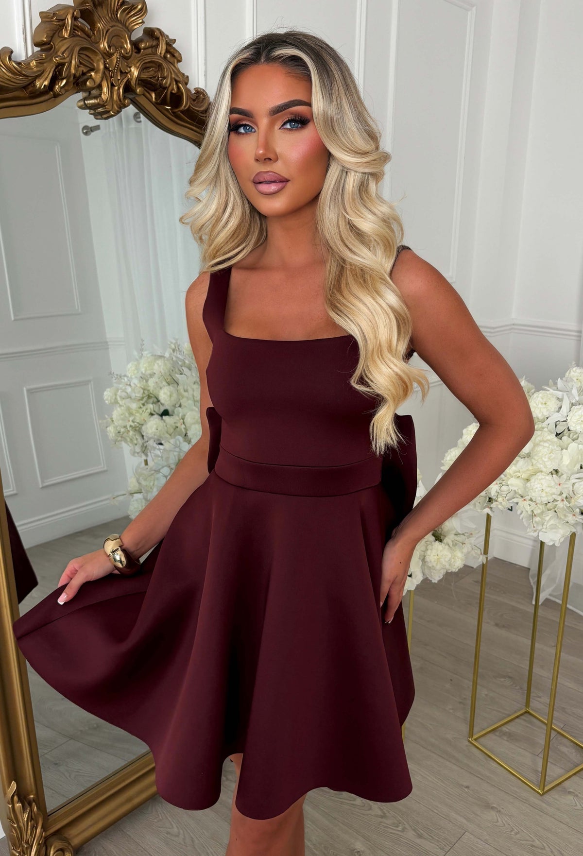 Back view of a burgundy bow back mini dress with a deep V back, oversized bow detail and flared mini skirt.