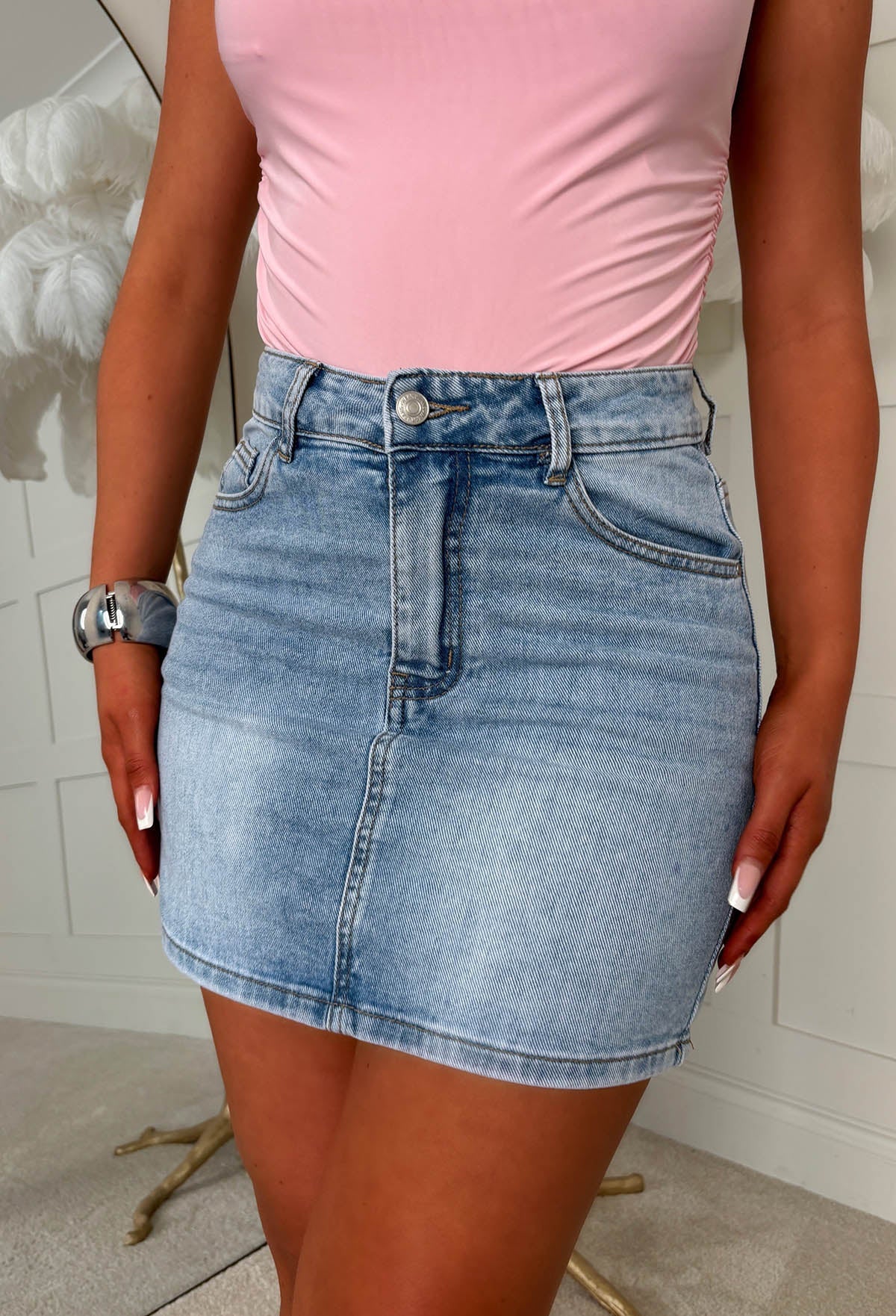 Mid wash stretch denim mini skirt with pink crystal embellished back pocket and distressed details.