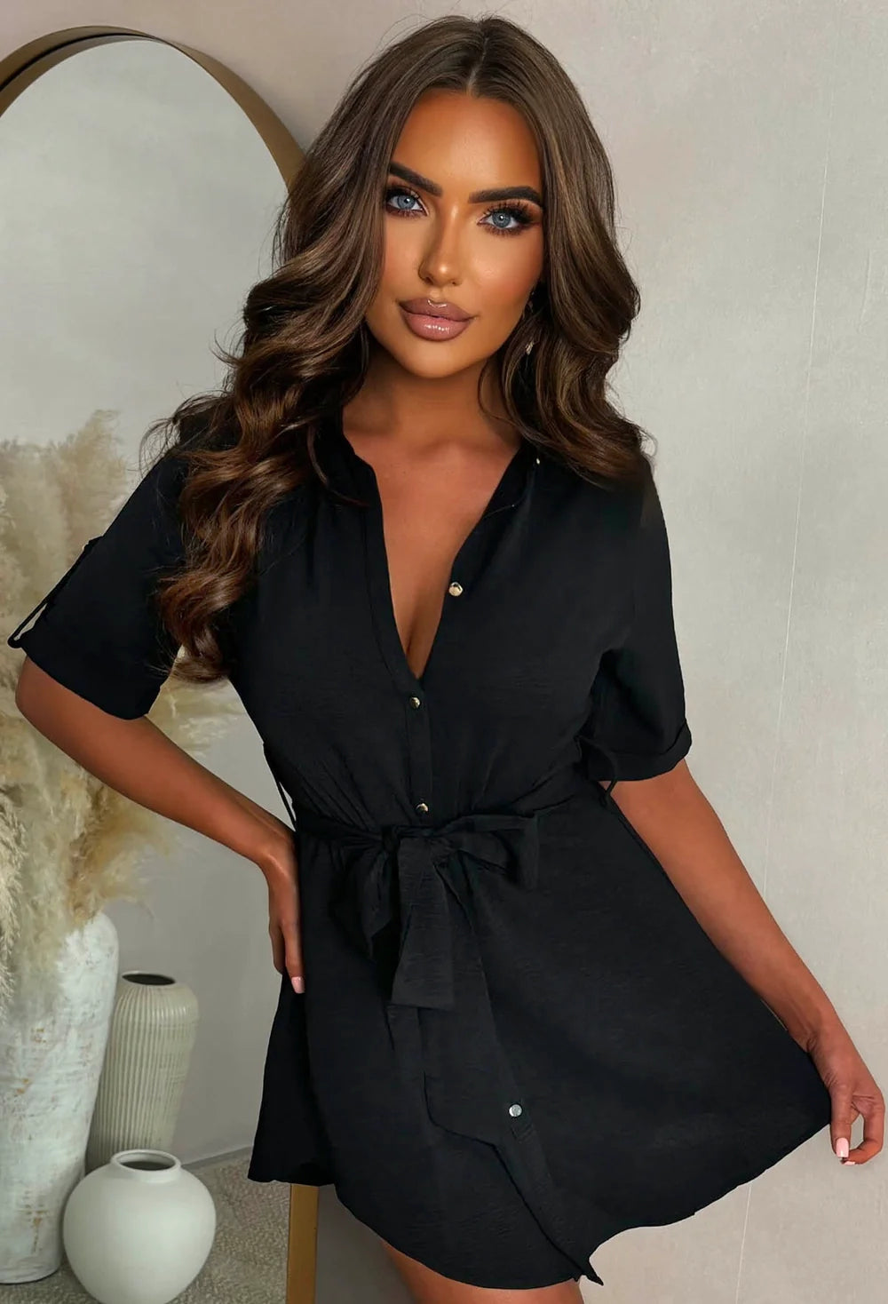 Black shirt dress with short sleeves, button front and belted waist, styled as a mini dress.