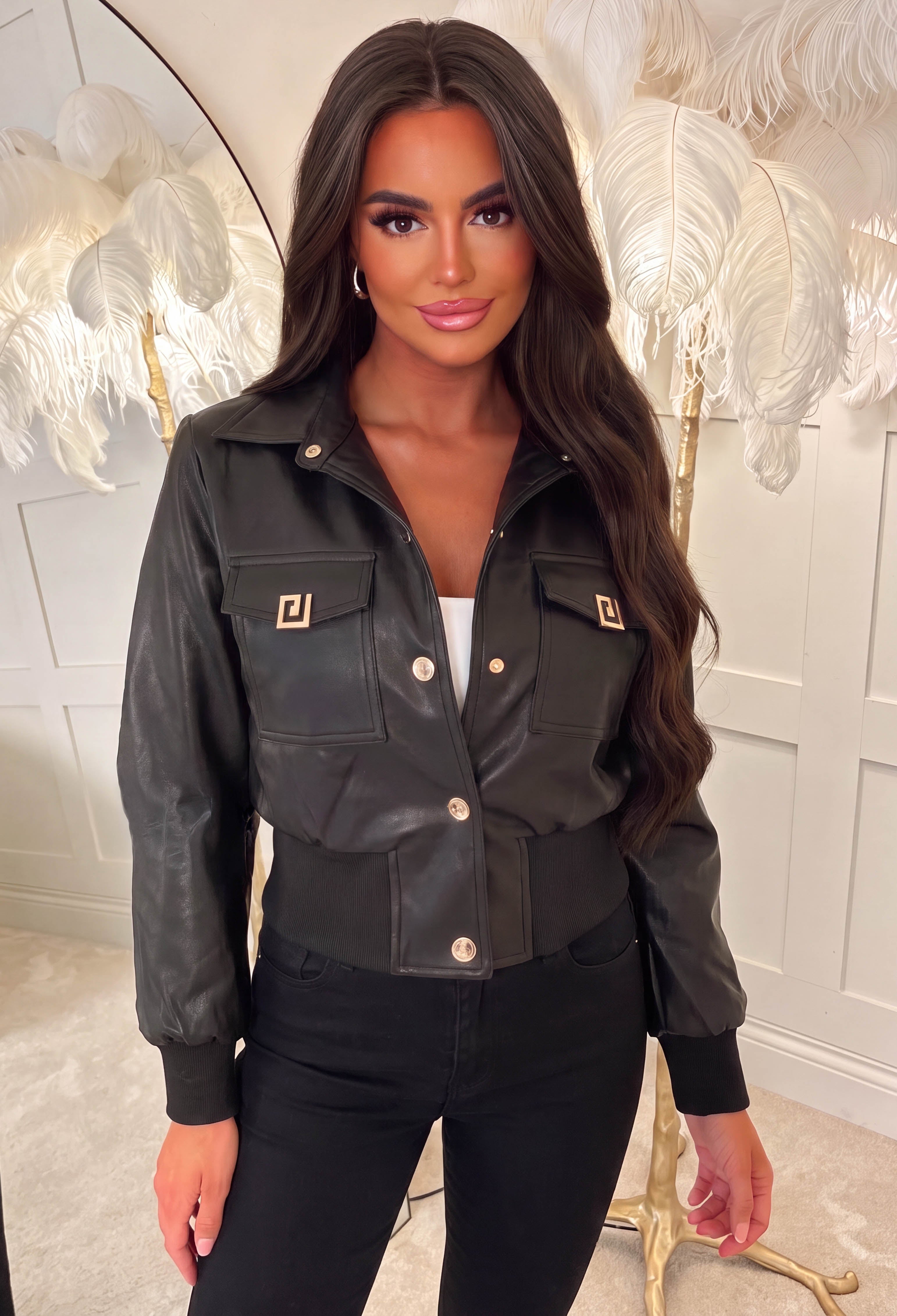 Black cropped faux leather jacket with gold buttons, logo details, front pockets and a cinched waist.