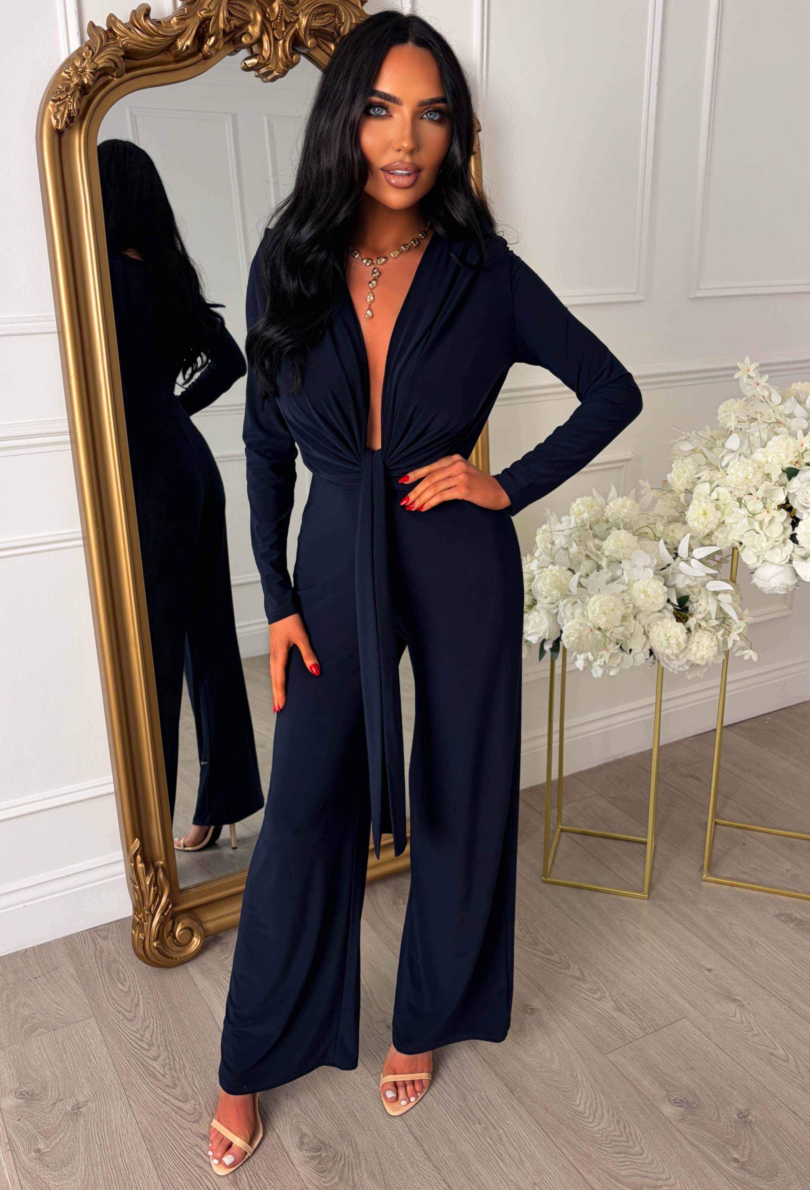 Navy stretch sleeveless plunge jumpsuit with a deep drape neckline, shoulder pads and wide-leg fit.