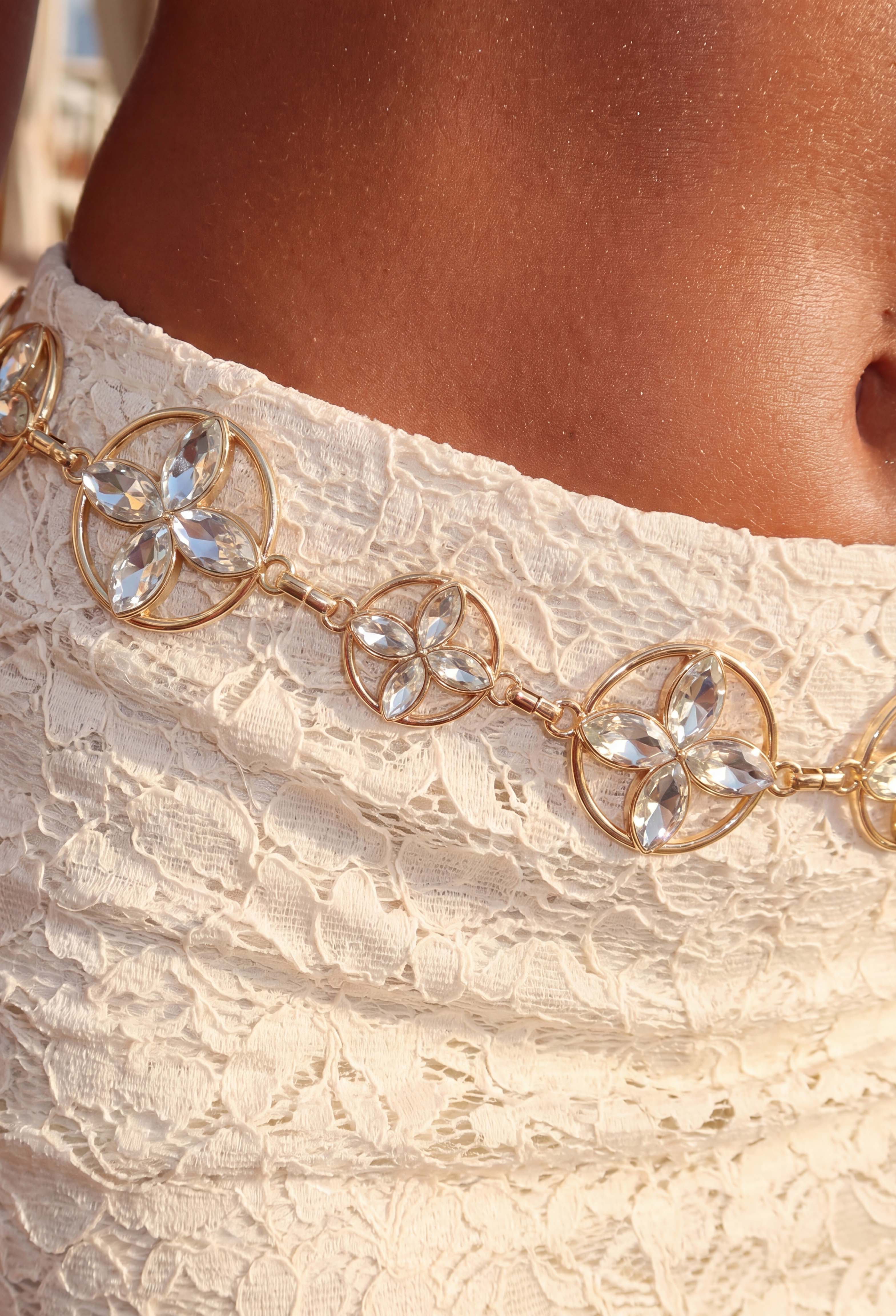 Close-up of a gold floral chain belt with crystal petal embellishments and adjustable links.