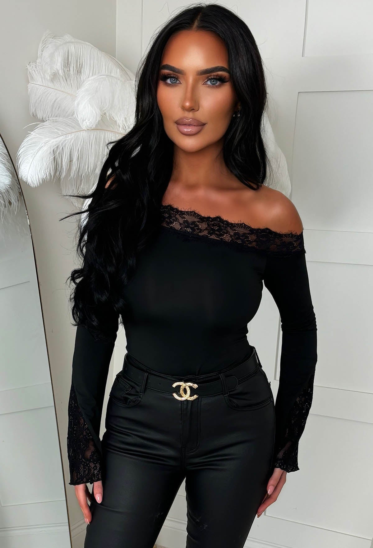 Black lace asymmetric neck flare sleeve top with delicate lace trim, fitted long sleeves and an angled neckline.