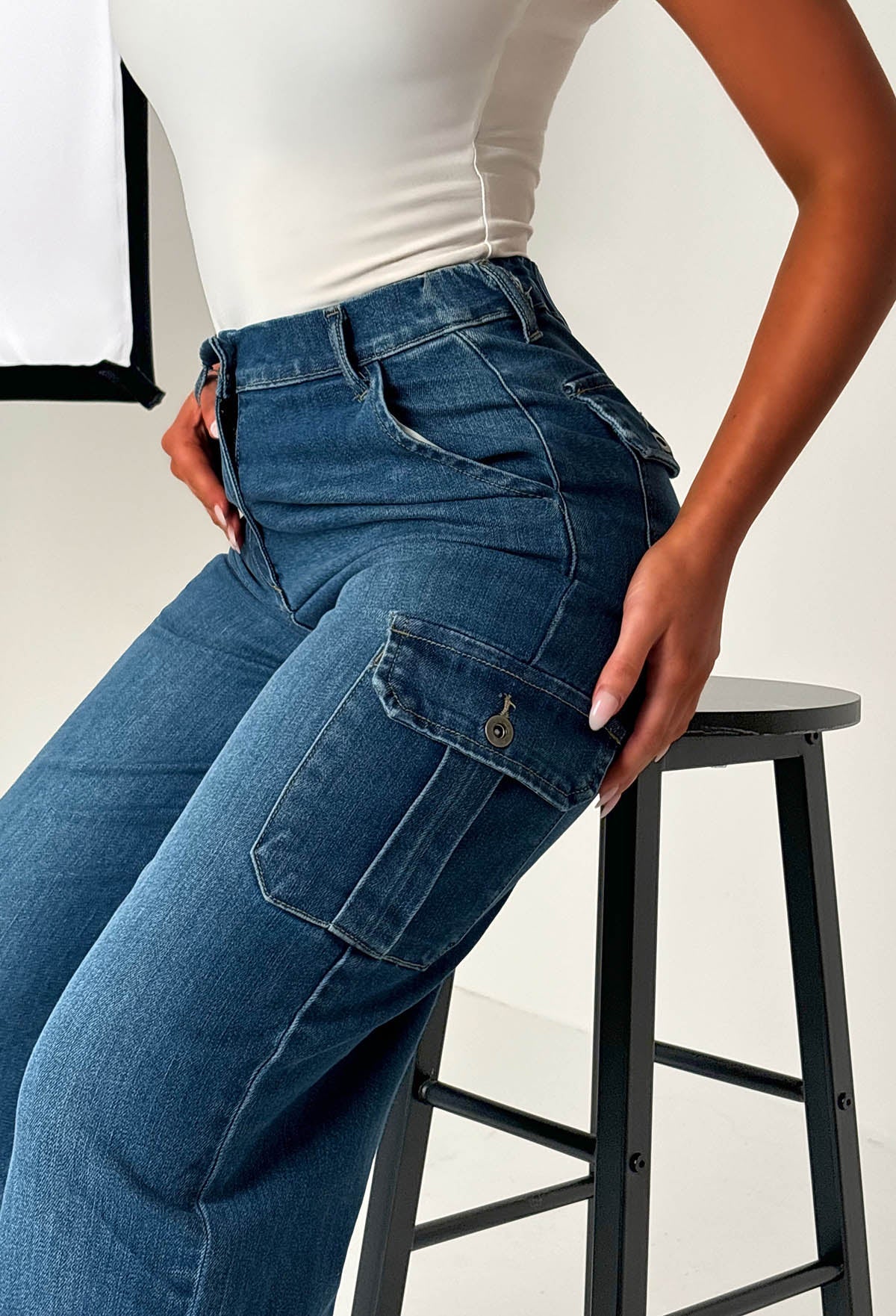 Back view of dark wash cargo denim wide leg jeans with flap pockets, relaxed loose fit and structured denim fabric.