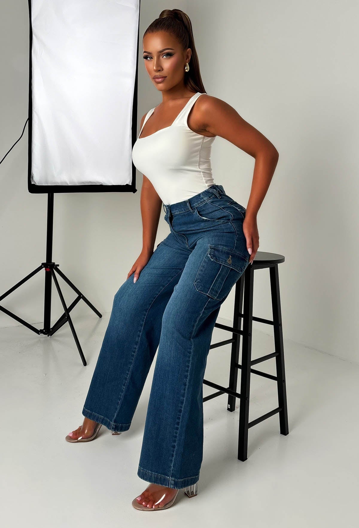 Back view of dark wash cargo denim wide leg jeans with flap pockets, relaxed loose fit and structured denim fabric.