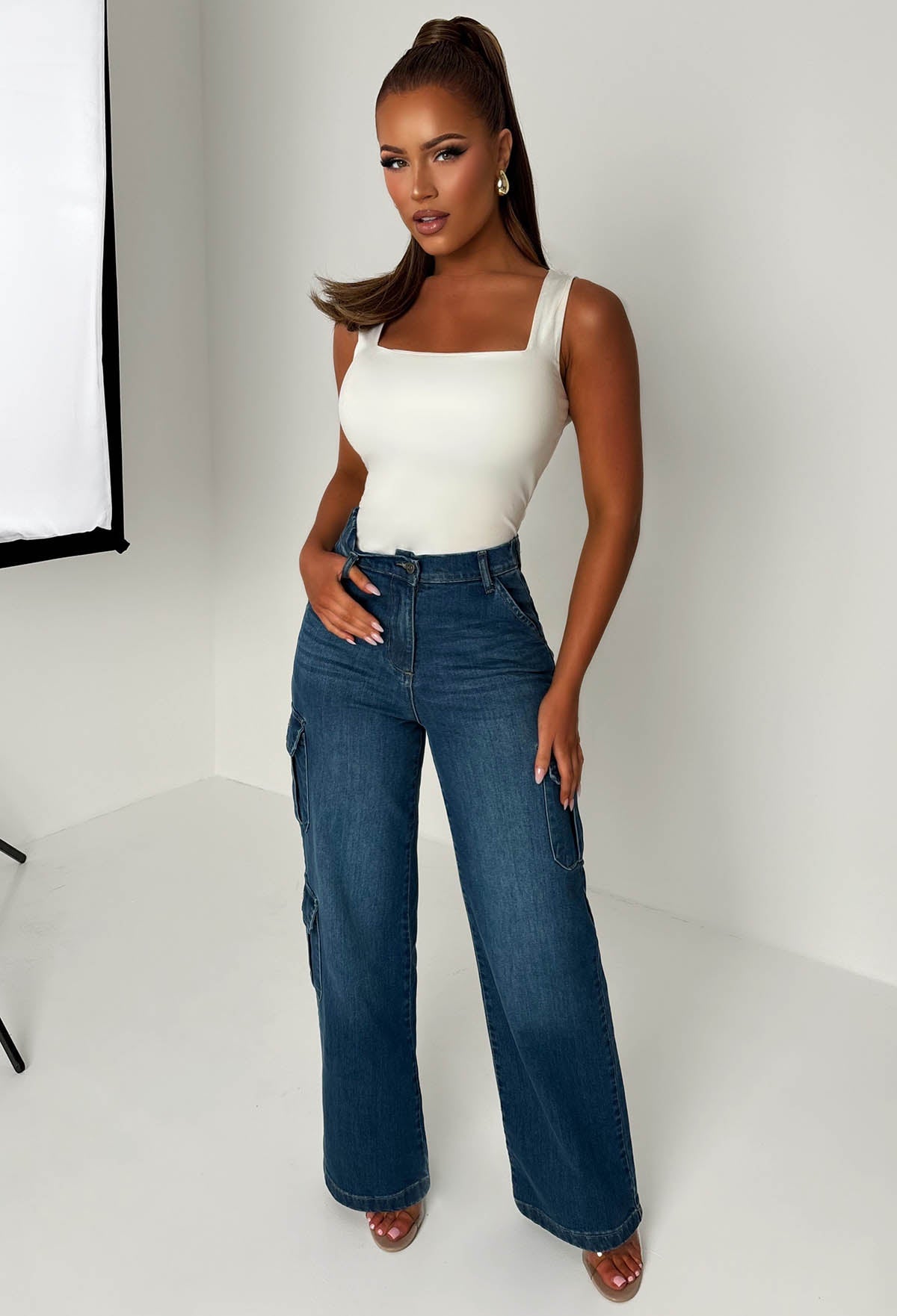 Back view of dark wash cargo denim wide leg jeans with flap pockets, relaxed loose fit and structured denim fabric.