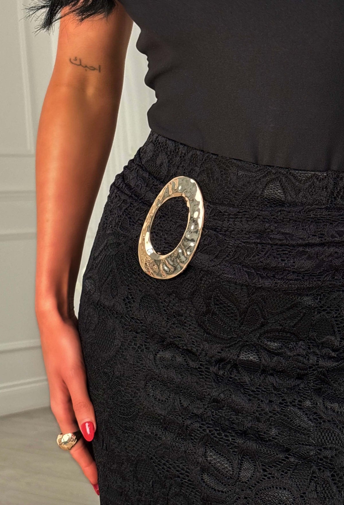 Black lace midi skirt with a statement buckle at the waist and a front leg slit.