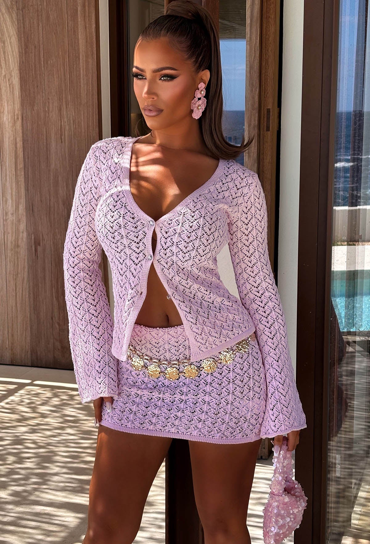 Light pink crochet mini skirt with a stretch waistband, open knit texture and a gold chain belt.