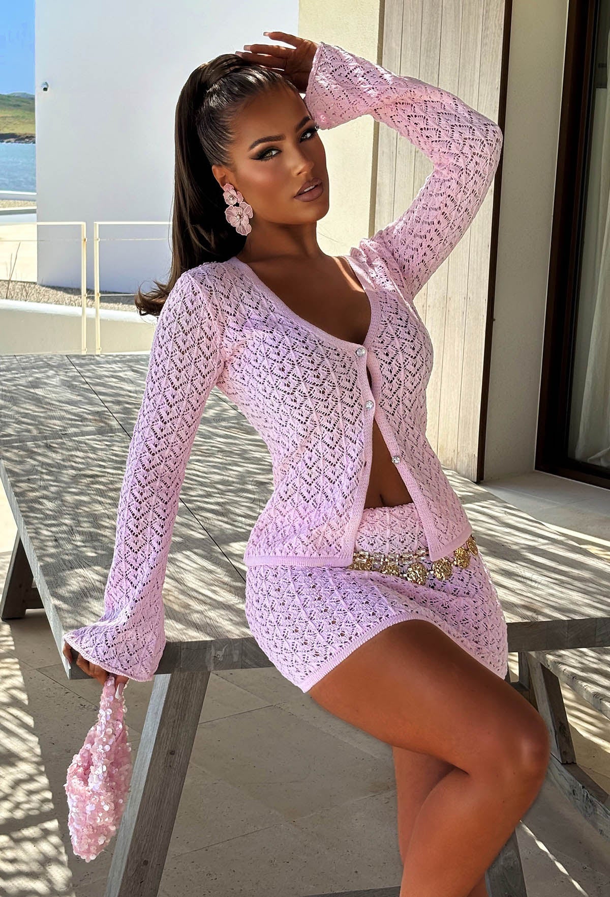 Light pink crochet mini skirt with a stretch waistband, open knit texture and a gold chain belt.