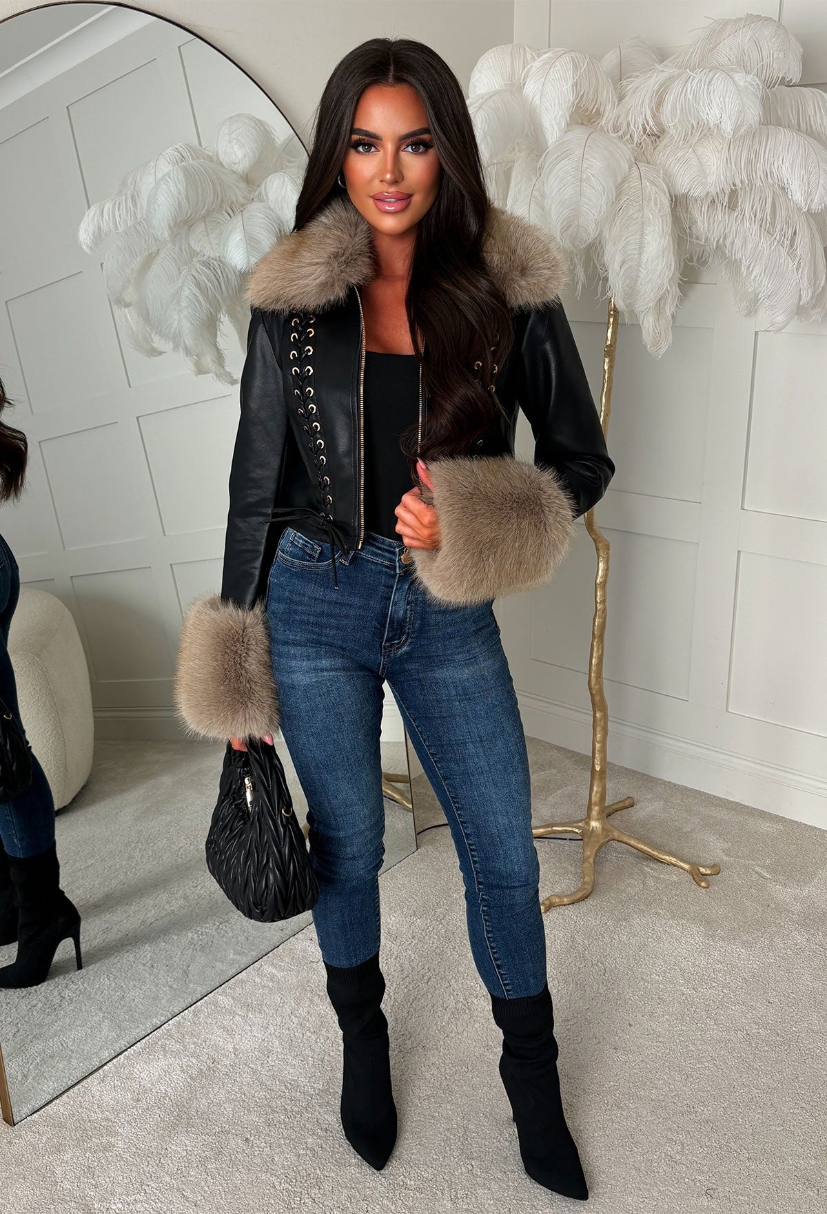 Black eyelet faux fur leather jacket with beige faux fur collar and cuffs, zip front, styled with ripped jeans.