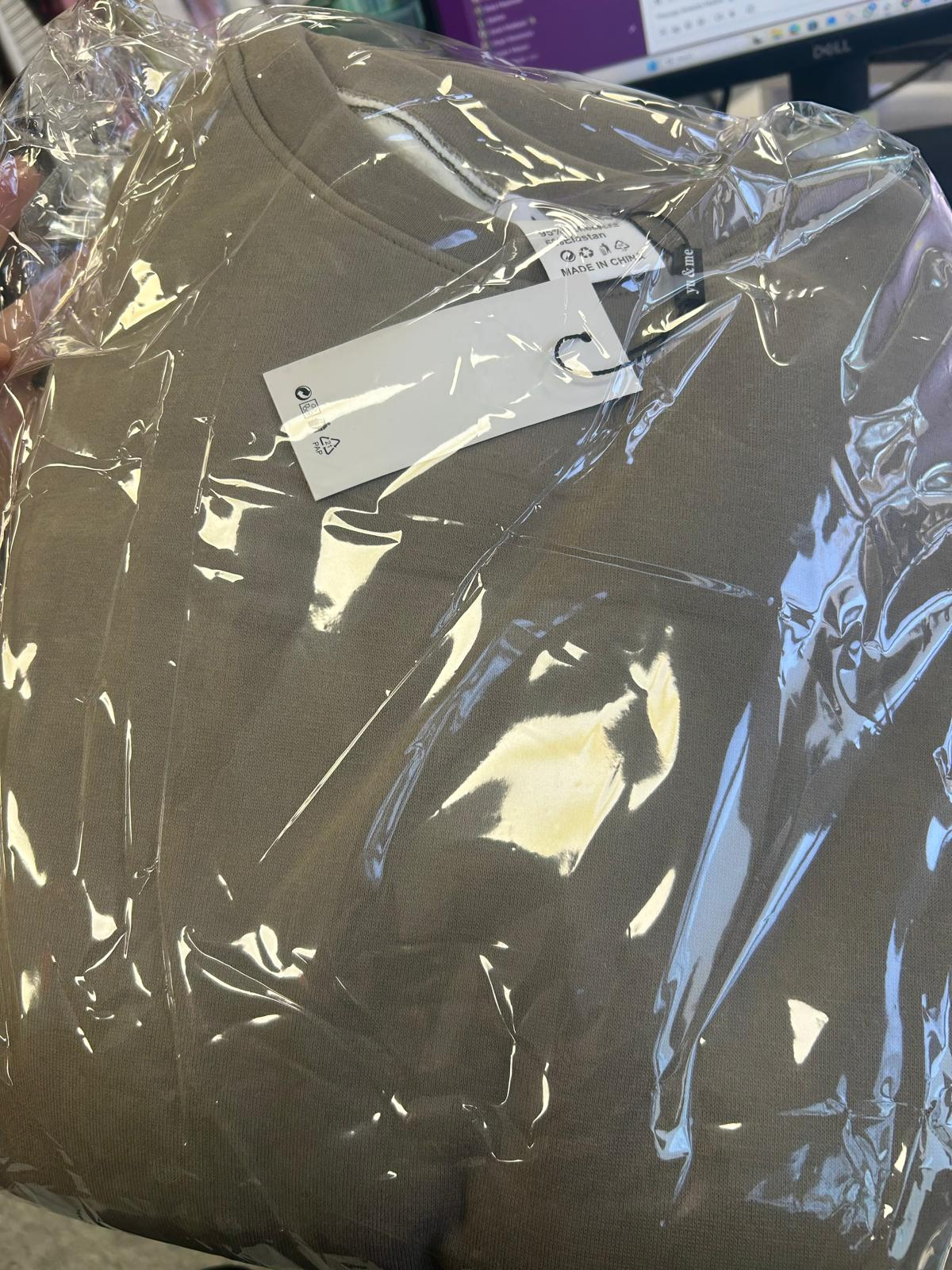 Flat lay of a brown basic lounge co-ord with a crew neck top in soft jersey fabric and relaxed fit, packaged in clear plastic.