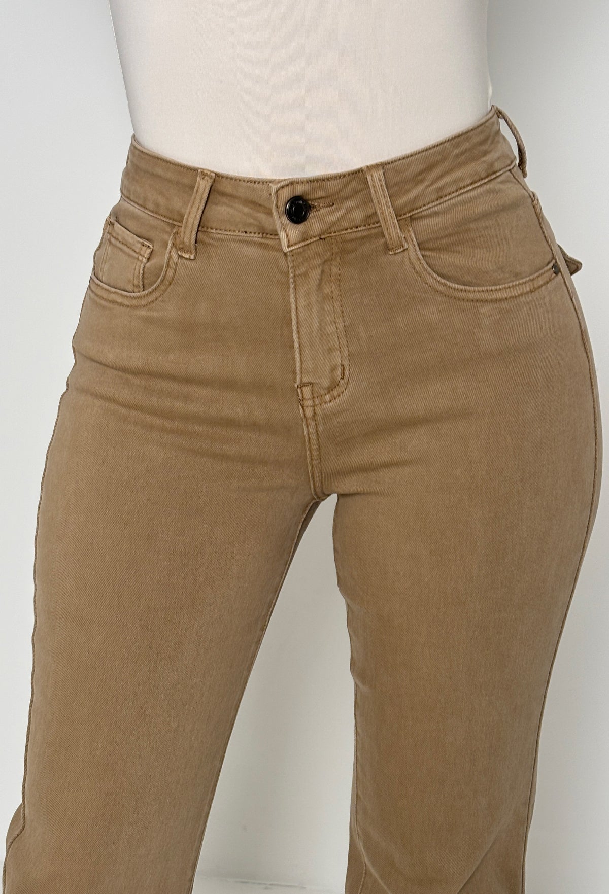 Back view of beige stretch fitted and flared mid rise jeans with flap back pockets and subtle seam detailing.