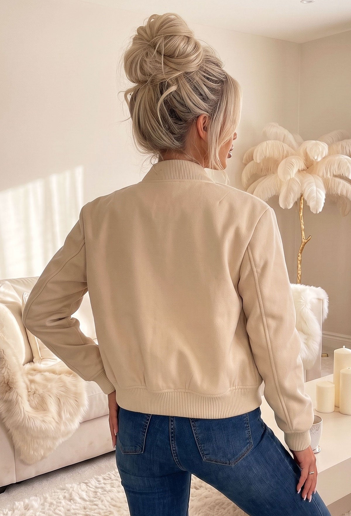 Beige front pocket bomber jacket with silver popper fastening, ribbed cuffs and hem, styled with light blue jeans.