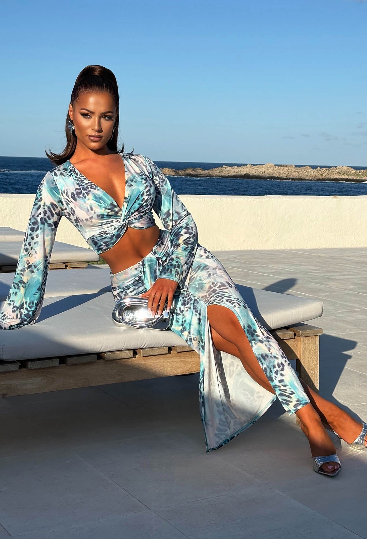Model in Holiday Villa sat wearing Blue Leopard Print Knot Front Top & Skirt Co-Ord Set Full Length Front View