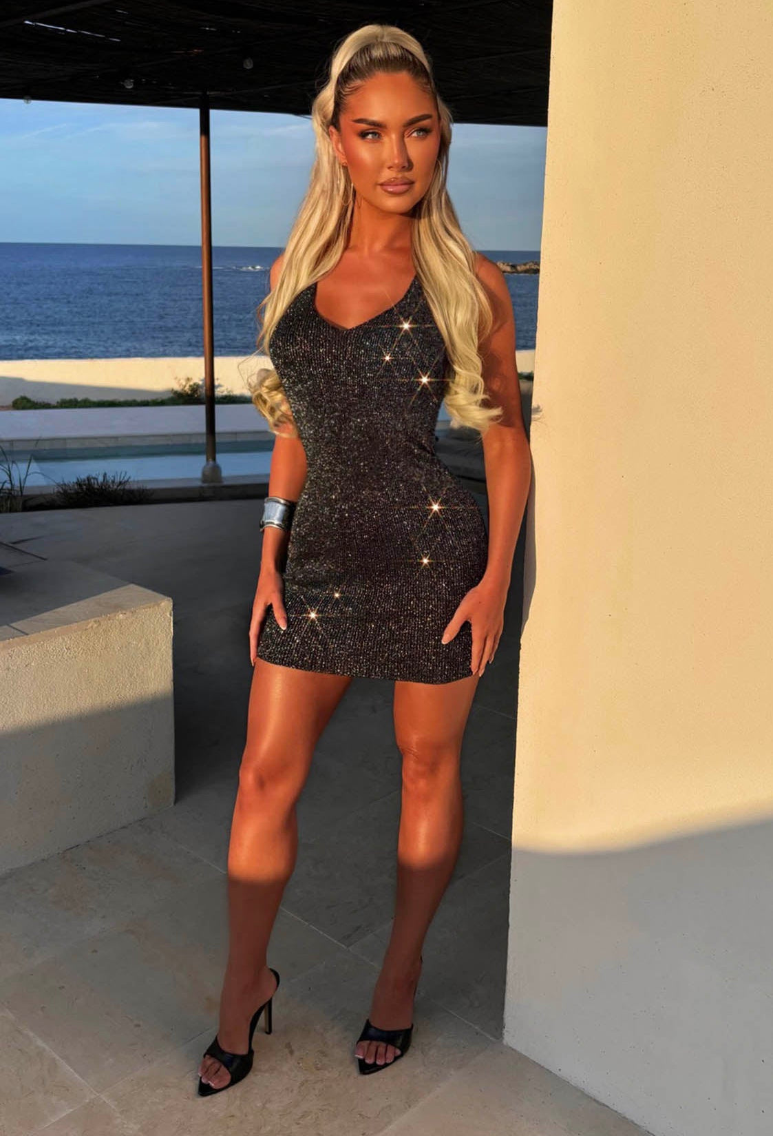 Model in Villa Wearing Black Knitted Halter Neck Lurex Mini Dress Full Length Front View