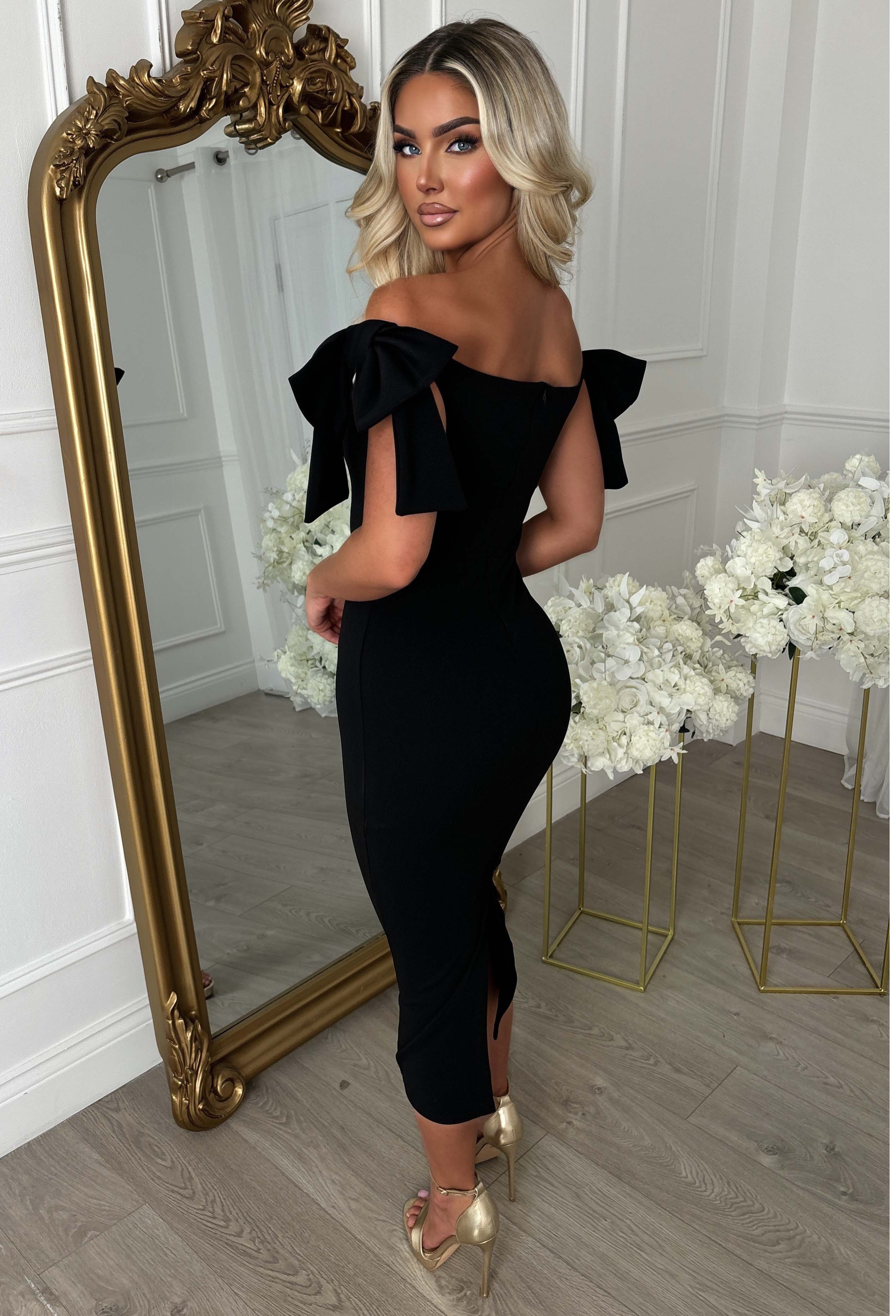 Black maxi dress with off-the-shoulder neckline, fitted silhouette and statement side bow detail.