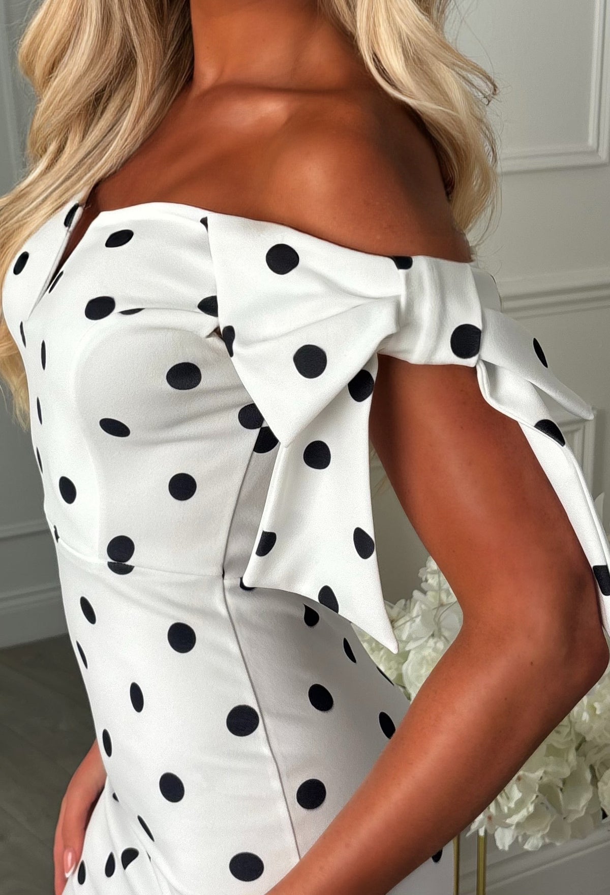 Monochrome polka dot midaxi dress with off-the-shoulder neckline, fitted silhouette and side bow detail.