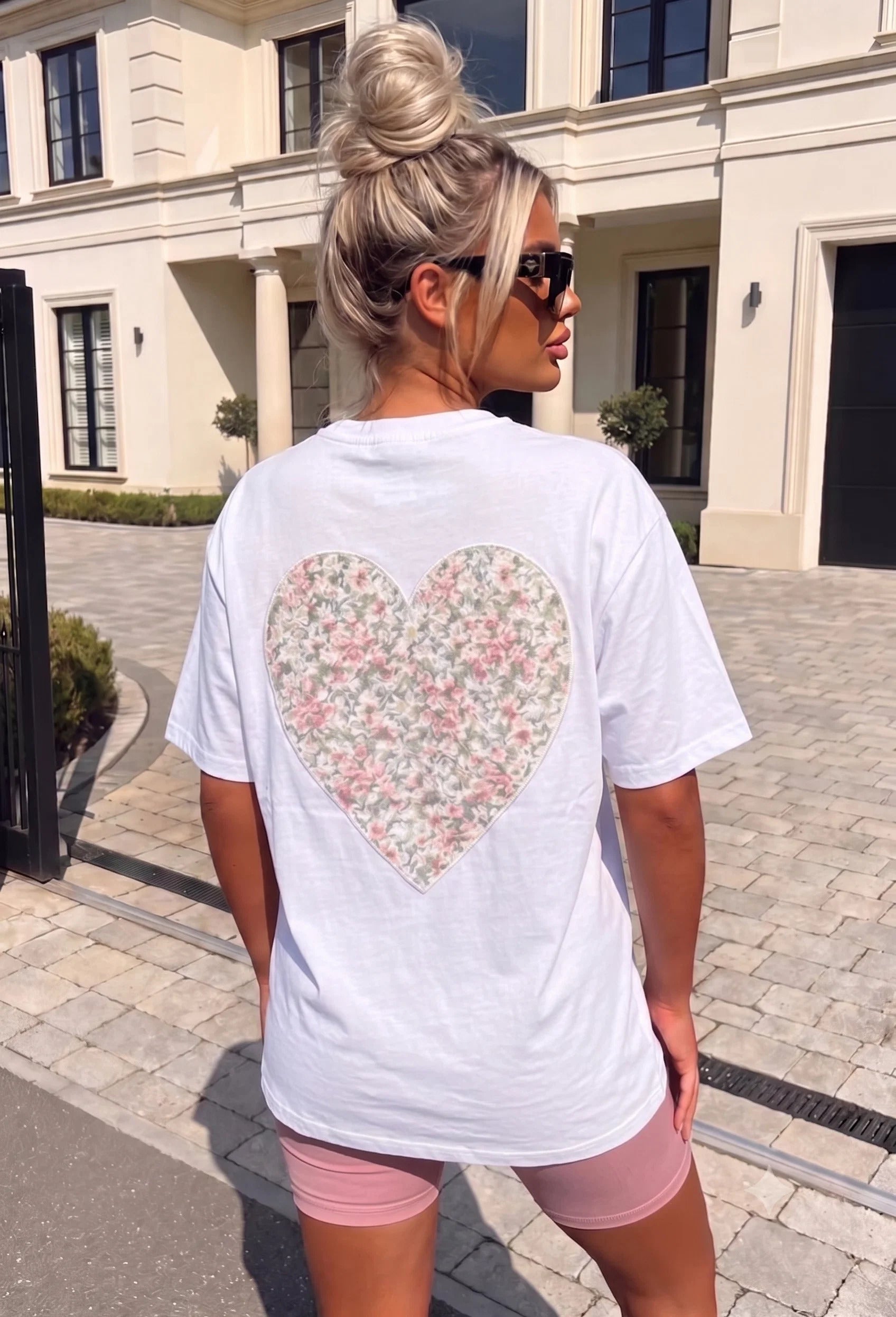 Back view of a white oversized T-shirt with an embroidered floral heart design.