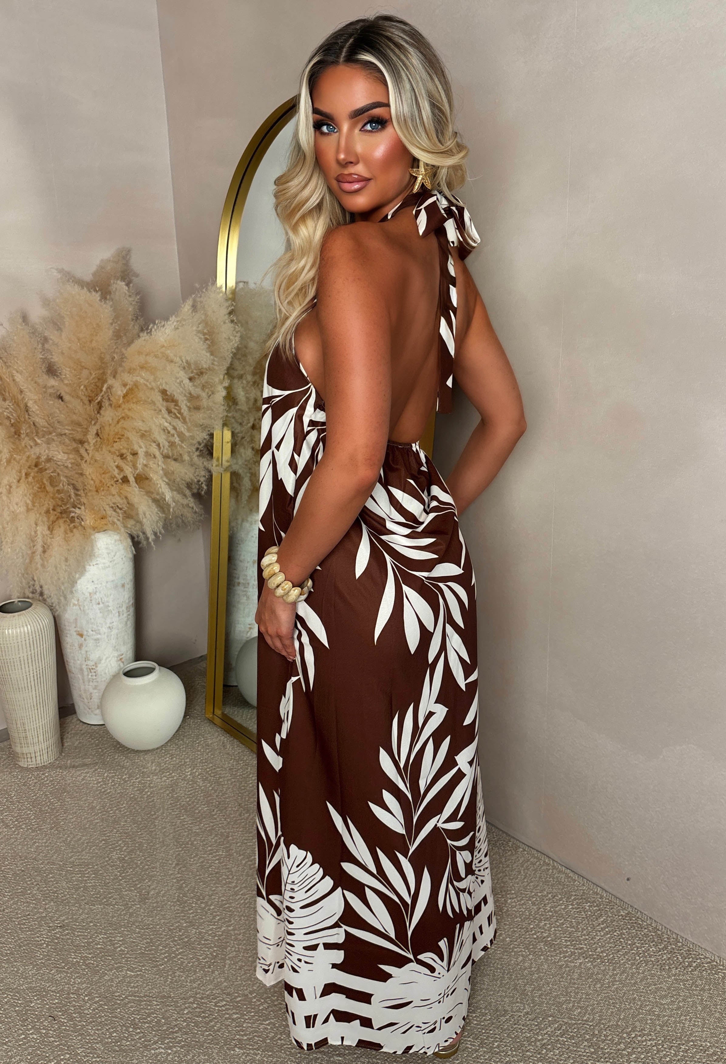 Brown palm print halter maxi dress with a high neckline, sleeveless cut and relaxed fit, styled poolside.
