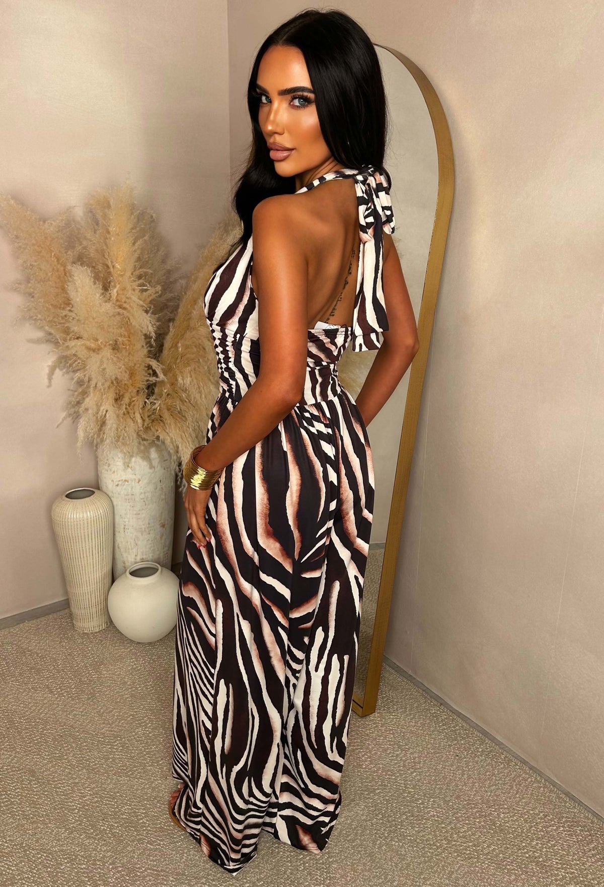 Brown animal print halter jumpsuit with a plunging neckline, tie fastening at the neck and wide leg silhouette.