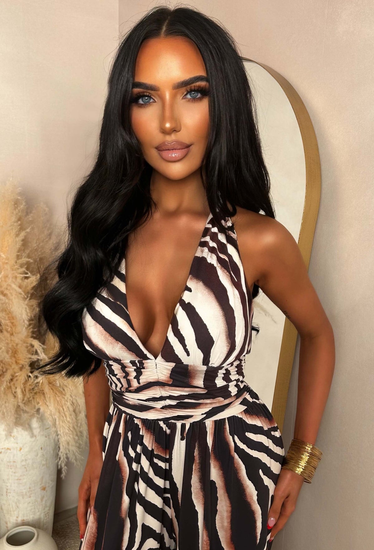 Brown animal print halter jumpsuit with a plunging neckline, tie fastening at the neck and wide leg silhouette.