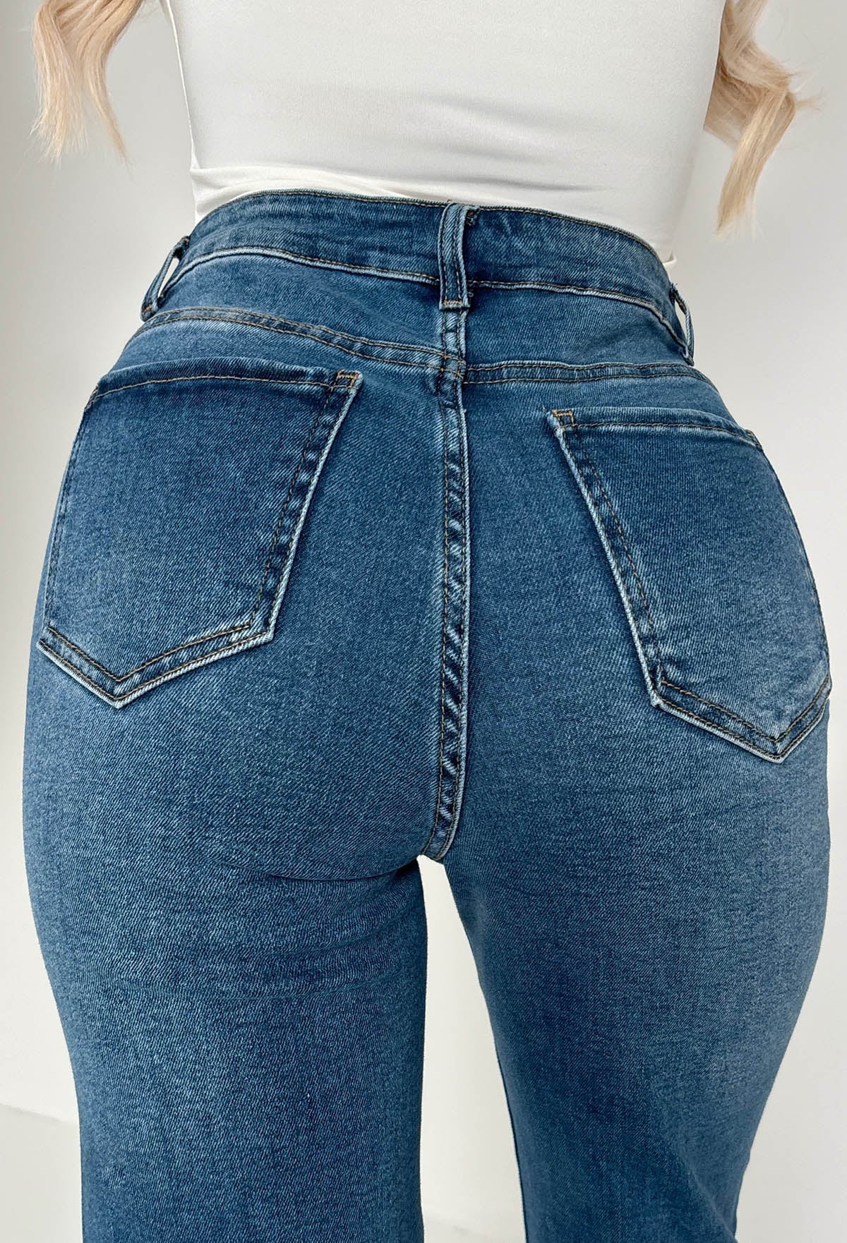 Back view of mid wash straight leg jeans with a high waist, classic five-pocket design and subtle fading.