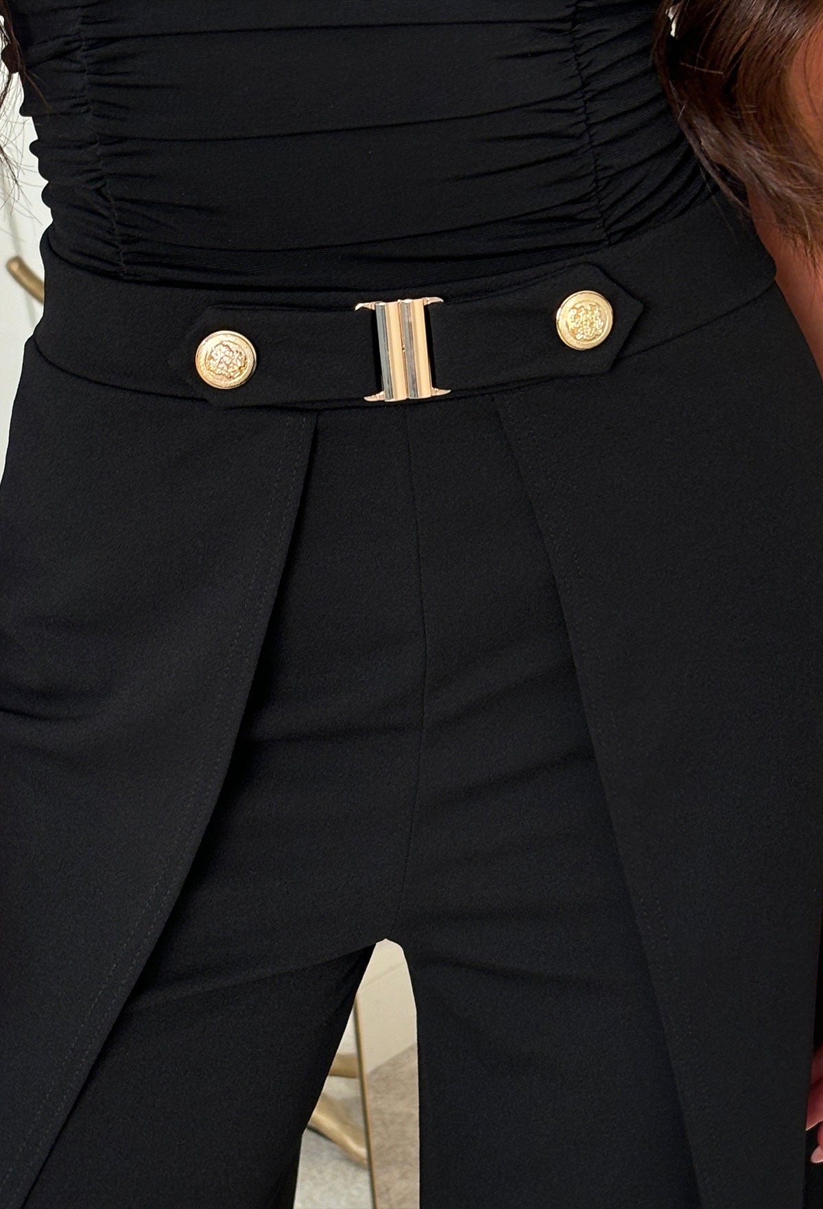 Black split hem trousers with gold button detail at the waist and a high-rise fit.