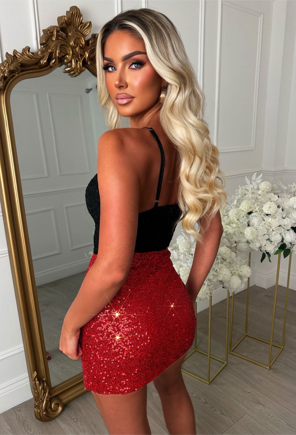 Red sequin mini skirt with a wrap front, gold buckle detail and fitted silhouette.