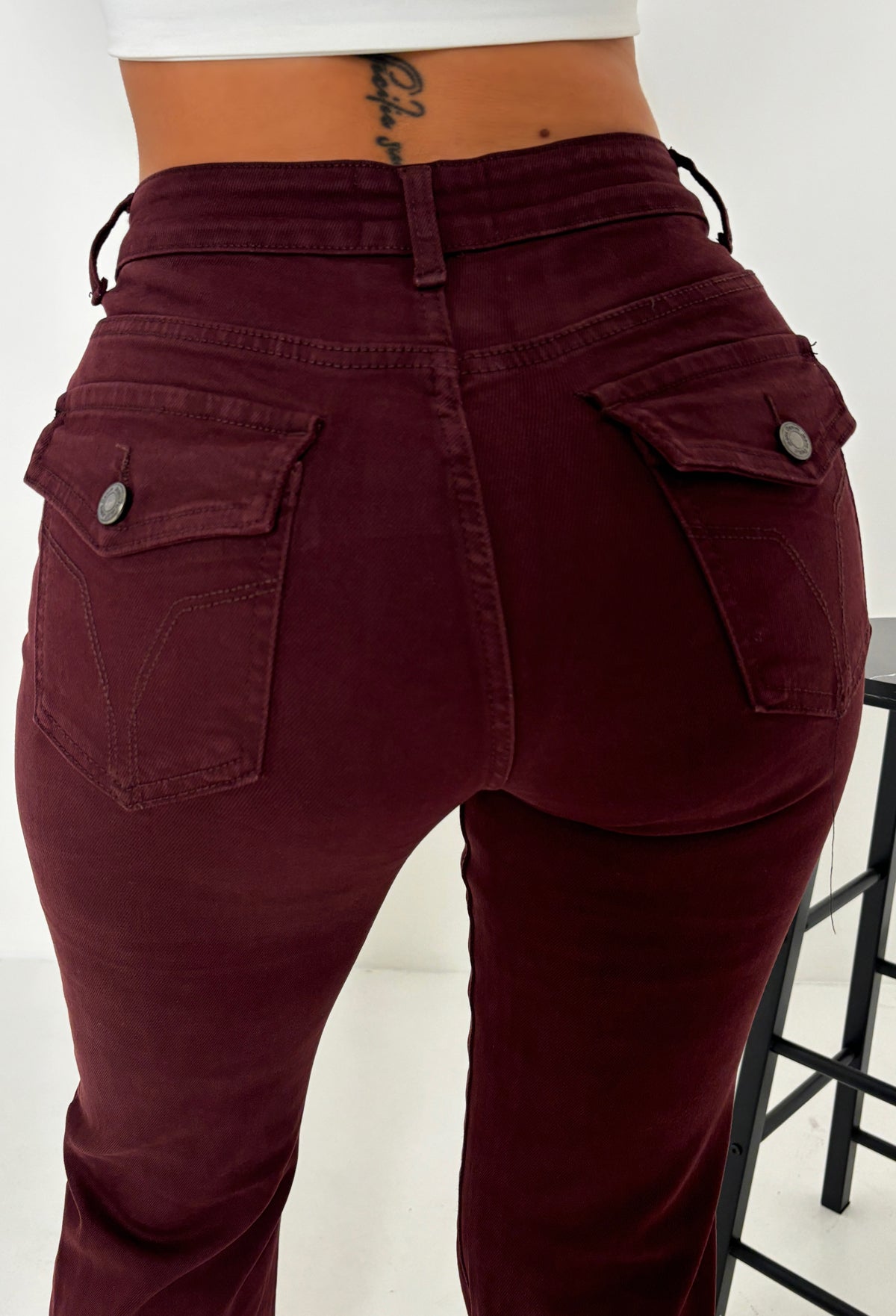 Back view of red stretch fitted and flared mid rise jeans with back pockets and a slim leg shape.