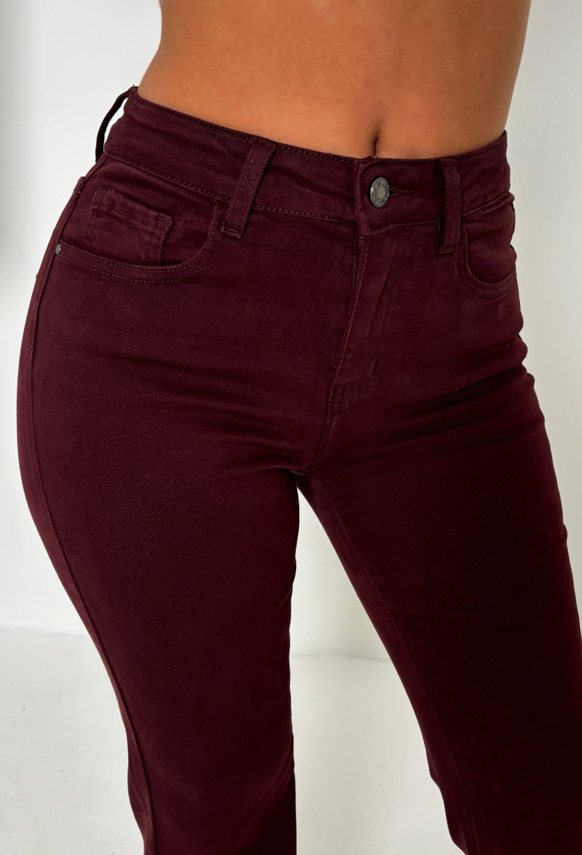 Back view of red stretch fitted and flared mid rise jeans with back pockets and a slim leg shape.