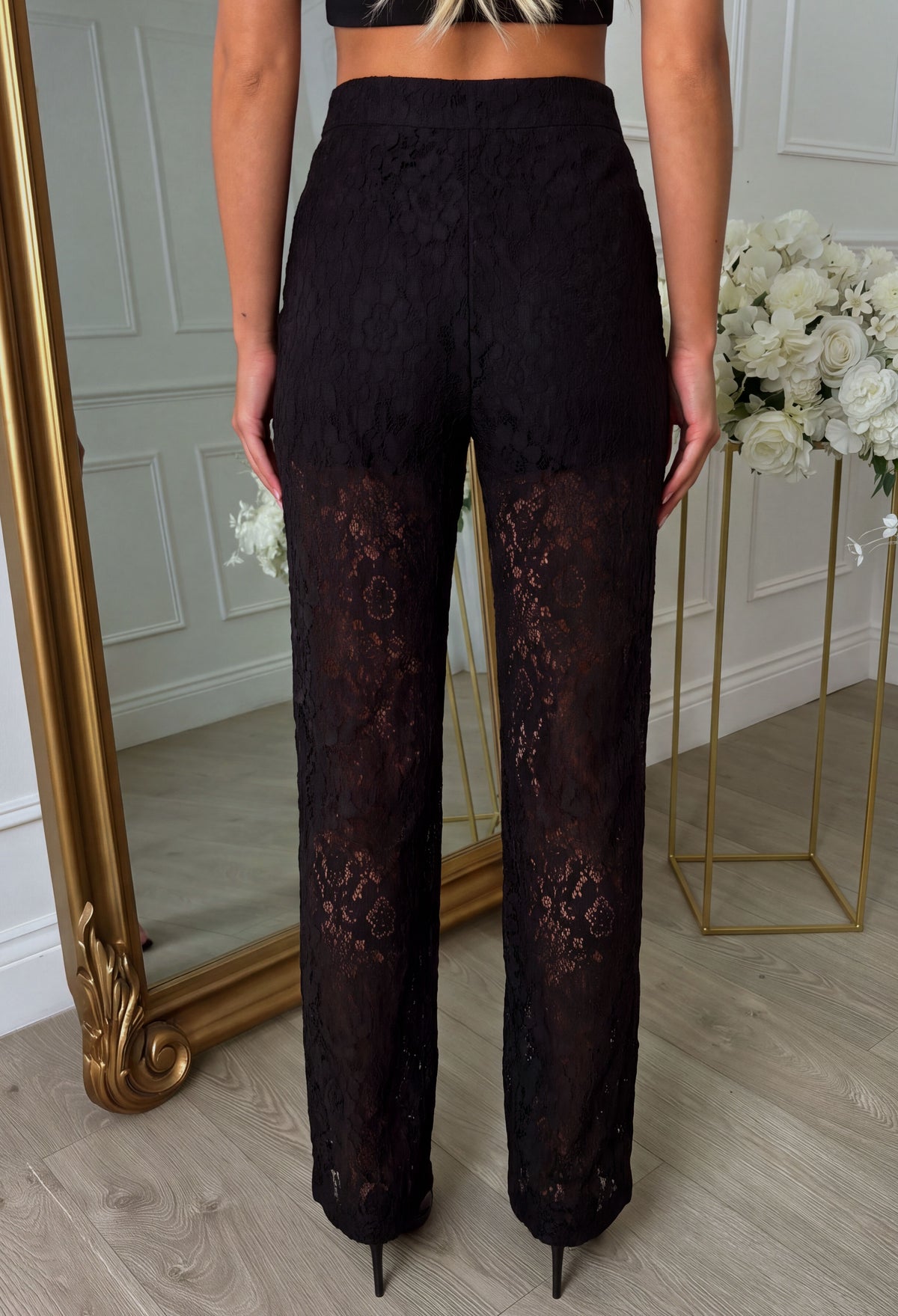 Black lace wide leg trousers in sheer floral lace fabric with a high waist, styled with a matching blazer.