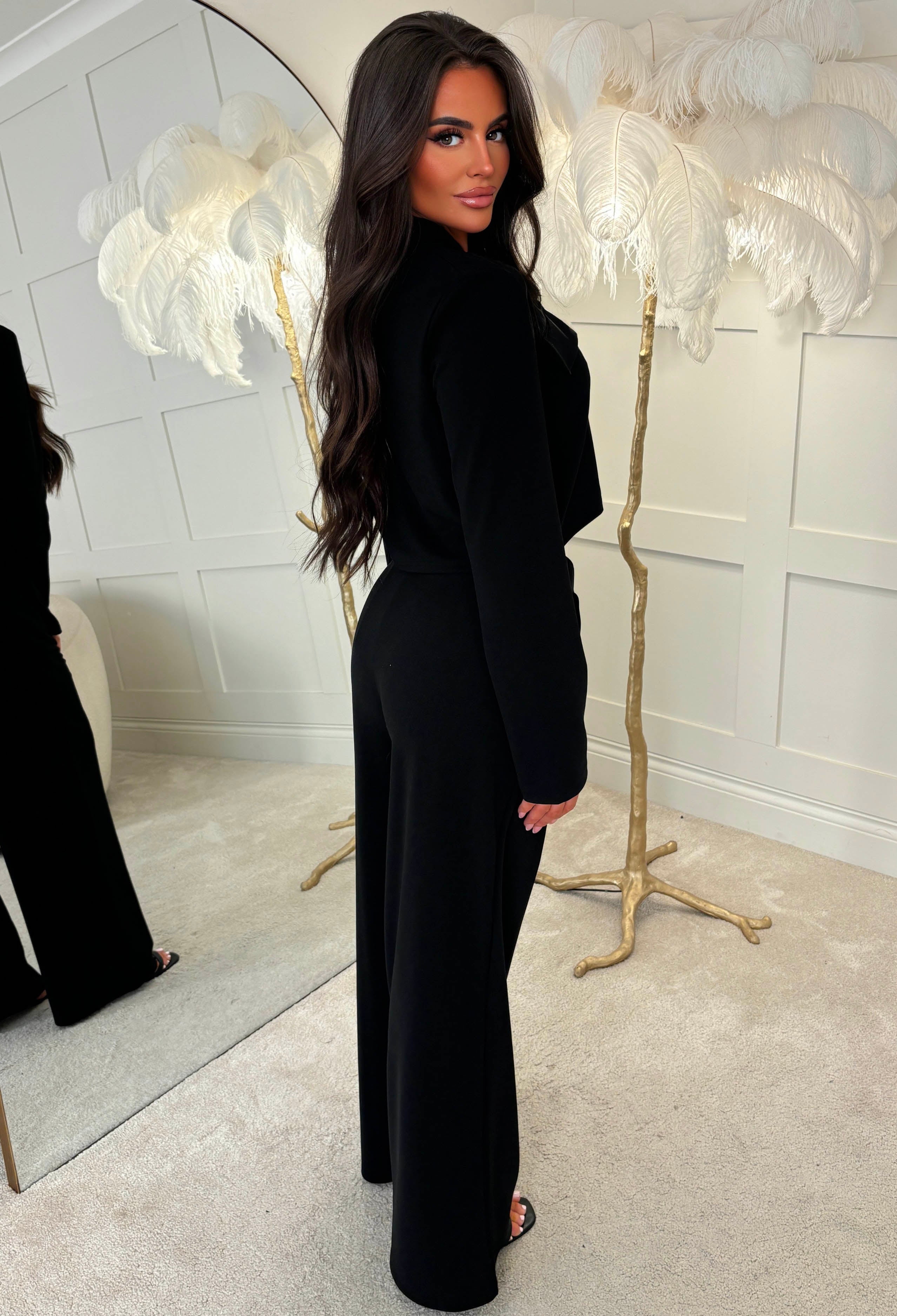 Black wide leg trousers with an elasticated waistband and relaxed fit, styled with white trainers and a chain strap bag.