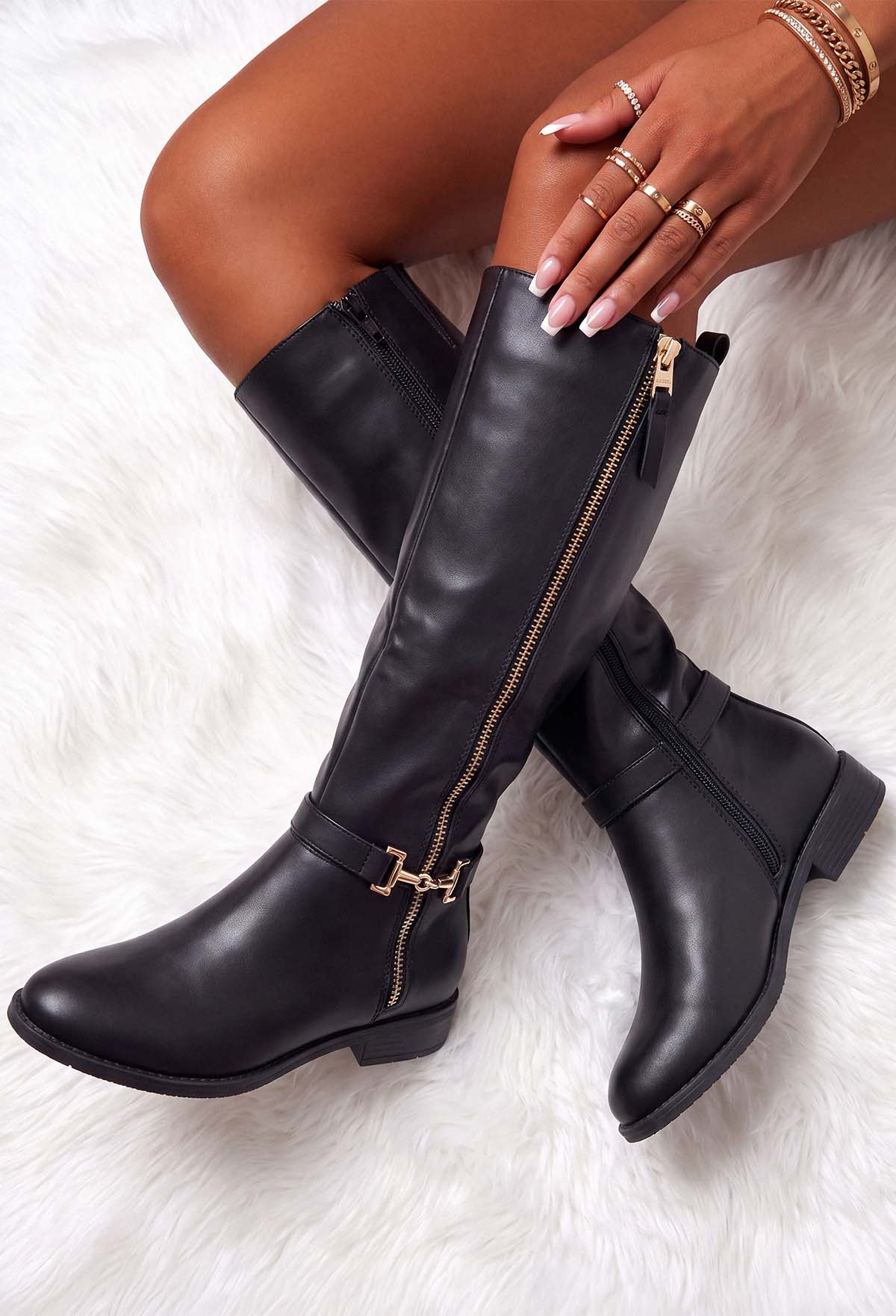 Black faux leather riding boot with a gold zip fastening and gold trim detail at the ankle.