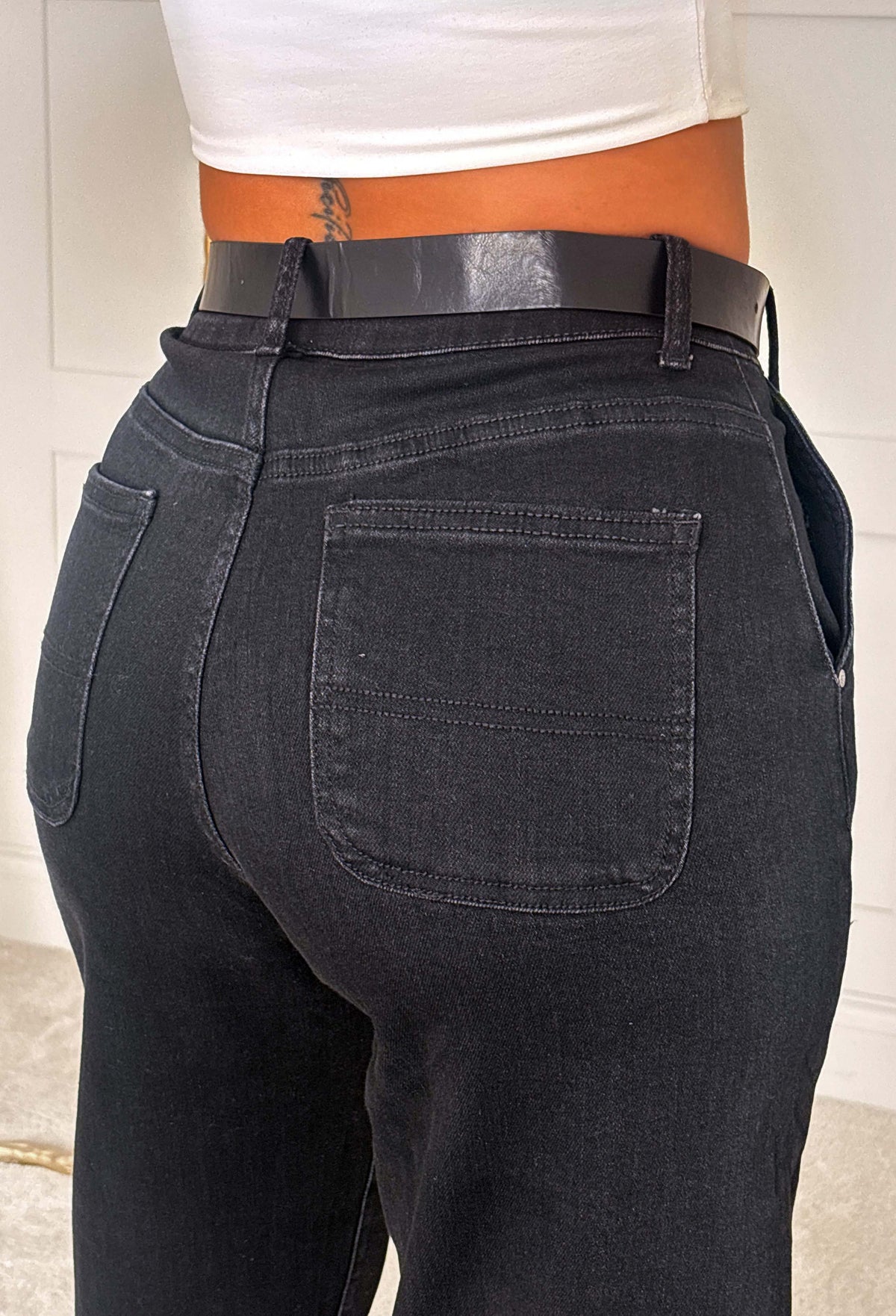 Black stretch denim barrel jeans with a high waist, barrel leg shape and matching black belt.