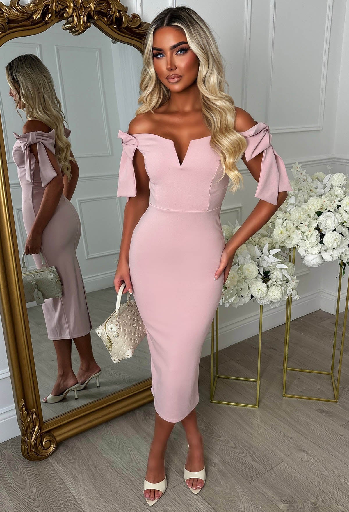 Pink midaxi dress with bardot off-shoulder neckline, fitted silhouette and statement side bow tie detail.